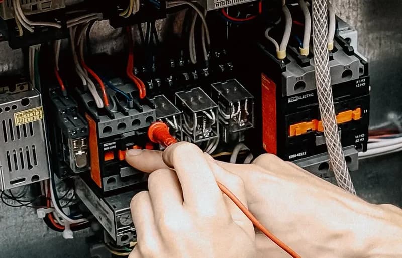 Elektriker prüft mit einem Multimeter die Verdrahtung in einem Schaltschrank.